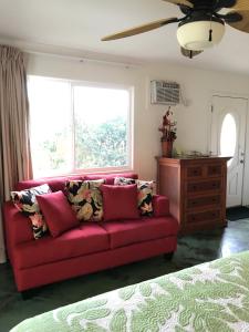 a red couch in a room with a window at Hale Pua Villa - Seaside Studio in Koloa