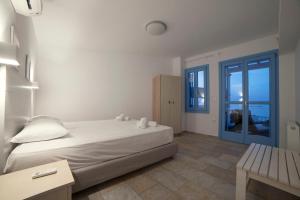 a white bedroom with a bed and a window at Almyra Guesthouse in Skiros