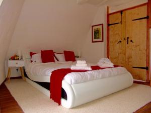 1 dormitorio con 1 cama blanca grande con almohadas rojas en FRANRÉAL, 4 Appartements en Sarlat-la-Canéda