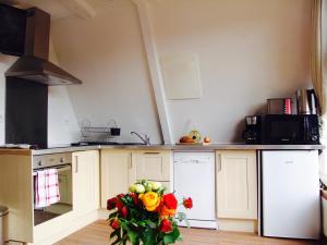 a kitchen with white cabinets and a vase of flowers at FRANRÉAL, 4 Appartements Climatisés in Sarlat-la-Canéda