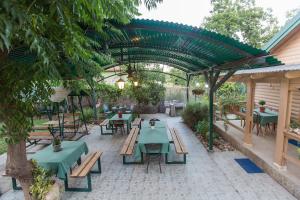um pátio exterior com mesas verdes e bancos em Leyad Hashmura Lodging em Yesud HaMa'ala