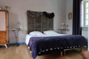 ein Schlafzimmer mit einem großen Bett mit einer blauen Decke in der Unterkunft Le Relais Du Grand Logis in Civrieux