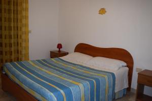 アルカモ・マリーナにあるVillino Relax vicinissimo alla spiaggiaのベッドルーム1室(青と黄色のストライプ毛布付きのベッド1台付)
