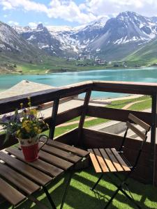 a wooden bench with a potted plant on a balcony with mountains at Grands studios vue sur lac in Tignes