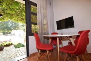 a dining room with red chairs and a table and a television at Apartments Pavić Valbandon in Fažana