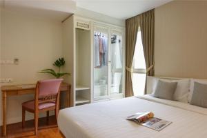 Un dormitorio con una cama, un escritorio y una silla. en Sabai Sathorn Service Apartment, en Bangkok