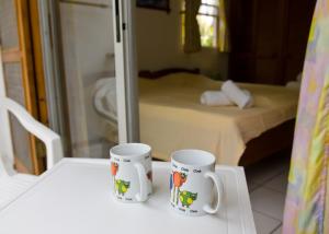 twee koffiemokken op een tafel in een slaapkamer bij Cherry Tree Apartments in Christ Church