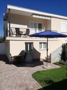 une terrasse avec une table et un parasol bleu dans l'établissement Apartman Anni, à Poreč