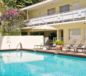 einem Pool mit Stühlen und einem Sonnenschirm neben einem Gebäude in der Unterkunft Ocean Lodge in Boca Raton