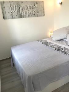 a white bed in a room with a sign on the wall at Buenavista Apartment in Sitges +34 photos