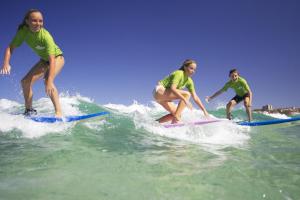 three girls riding a wave on surfboards in the ocean at Sienna Lodge in Yallingup