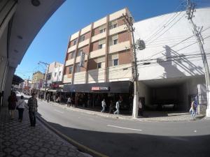 un grupo de personas caminando por una calle al lado de un edificio en Hotel Sao Nicolau, en Taubaté