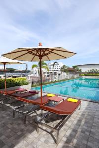 una piscina con varias tumbonas y una sombrilla en The Whisper Hotel en Pattaya centro