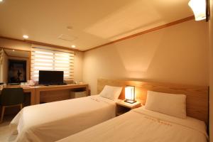 a room with two beds and a desk with a computer at Angel Hotel in Busan +68 photos