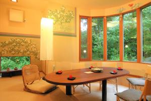 a living room with a table and some windows at Hanafubuki in Ito