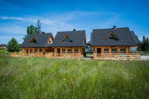 Due case di tronchi sono sedute in un campo di Osada Stary Bór a Murzasichle