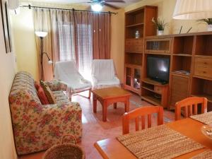 sala de estar con sofá, sillas y TV en Chipionabeachhouse, en Chipiona
