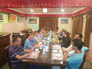 een groep mensen die aan een lange tafel zitten bij Bhaktapur Paradise Hotel in Bhaktapur