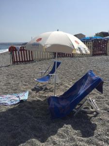 two chairs and an umbrella on a beach at Casa Vacanze Samira in Fondachello