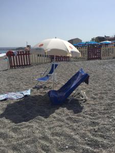 two chairs and an umbrella on a beach at Casa Vacanze Samira in Fondachello