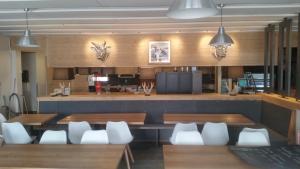 une salle à manger avec des tables en bois et des chaises blanches dans l'établissement Hôtel Le Relais Alpin, à Les Mosses