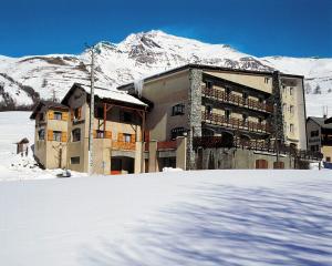 a building in the snow in front of a mountain at Les Agneaux in Villar-dʼArène