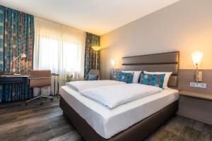 a bedroom with a large bed and a desk at Hotel Scheffelhöhe in Bruchsal