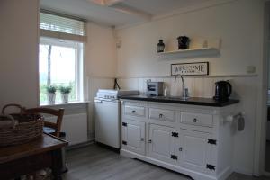 a kitchen with white cabinets and a sink and a window at B&B Droom 44 in Buinerveen
