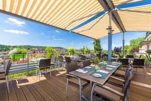 eine Holzterrasse mit Tischen und Stühlen auf dem Balkon in der Unterkunft Hotel Scheffelhöhe in Bruchsal