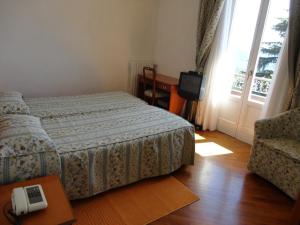 a bedroom with a bed and a tv and a window at Hotel Villa Rosy in Premeno