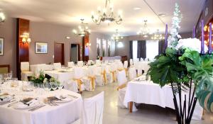 un salón de banquetes con mesas blancas, sillas y flores en Casa Santos, en Albalate de Cinca