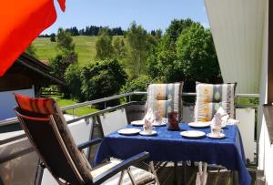 einen Tisch mit einem blauen Tischtuch und Stühlen auf dem Balkon in der Unterkunft Haus Deutsch in Roßhaupten