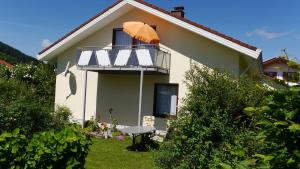 a small house with a balcony with an umbrella at Haus Deutsch Berg-See- und Schloss Neuschwanstein Nähe in Roßhaupten
