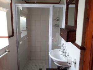 ein weißes Badezimmer mit Waschbecken und Dusche in der Unterkunft De Kothuize 10 in Graaff-Reinet