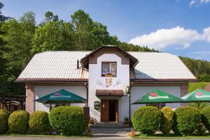 a small white building with green umbrellas at Hotýlek u Kance in Lipova Lazne