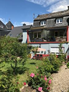 ein Haus mit einem Hof mit rosa Blumen in der Unterkunft Ferienwohnungen Perlina Karpat in Bernkastel-Kues