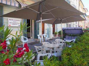 un patio con tavoli, sedie e ombrellone di Hotel Massimo a Viareggio