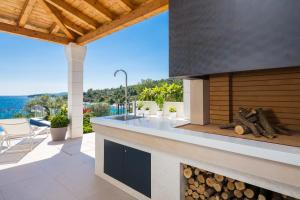 an outdoor kitchen with a fireplace and a view of the ocean at Villa Argemonia in Trogir