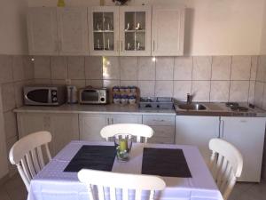 a kitchen with a table with white chairs and a kitchen with a sink at Apartment Antonija in Povile