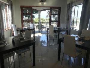 a dining room with black tables and white chairs at Villa Tropicana - South Africa in Margate