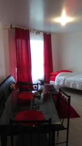 Cette chambre comprend deux lits, une table et des rideaux rouges. dans l'établissement Appartements Sully, à Mantes-la-Jolie