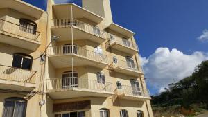 ein hohes Gebäude mit Balkon an der Seite in der Unterkunft Kaccatur Flats in Marsalforn