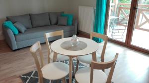 uma sala de estar com uma mesa e cadeiras e um sofá em Apartament Anna Park Rodzinna em Mielno