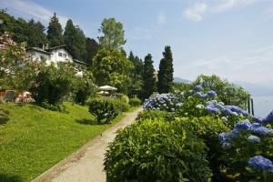 a path through a garden with flowers and a house at Residence del Pascia' in Oggebbio