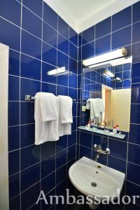 La salle de bains est pourvue de carrelage bleu, d'un lavabo et d'un miroir. dans l'établissement Hotel Ambassador - Free Parking, aux Sables d'or