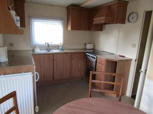 a small kitchen with wooden cabinets and a sink at Fenlake holiday accommodation in Metheringham +11 photos