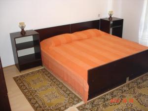un letto con copriletto arancione e 2 comodini di Apartman Klimic a Umag (Umago)