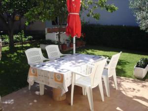 tavolo con sedie bianche e ombrellone rosso di Apartman Klimic a Umag (Umago)