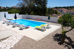 uma piscina com espreguiçadeiras e guarda-sóis em Casa do Loureiro Branco em Santarém