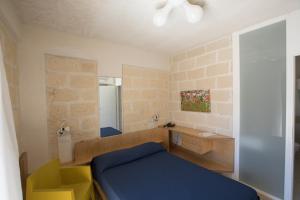 a small bedroom with a blue bed and a desk at Cave Bianche Hotel in Favignana